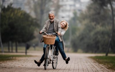 Happy mature couple having fun on a bicycle in autumn day at the park. Copy space.